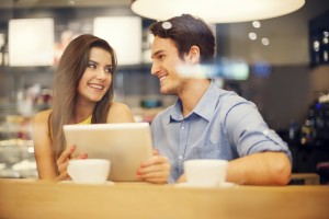 Flirting couple in cafe using digital tablet